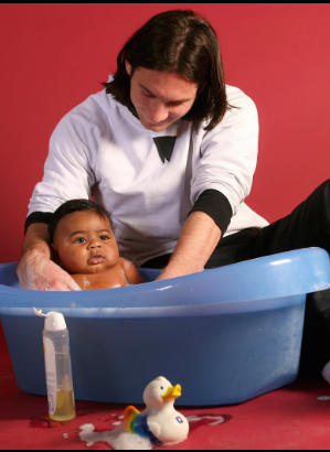 Close-up of Lionel Messi looking down at baby Lamine Yamal in the bath